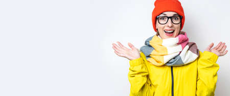 Cheerful surprised young girl in glasses, in a yellow jacket on a light background. Bannerの写真素材