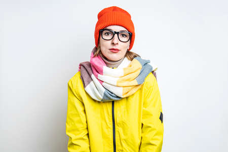 Sleepy young woman in glasses in a yellow jacket on a light background