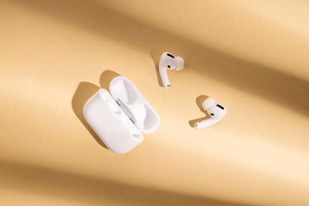 Wireless headphones on a beige background. Flat lay, top view