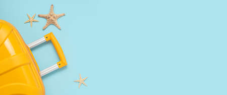 Yellow suitcase starfishes on a blue background. Top view, flat lay. Bannerの写真素材