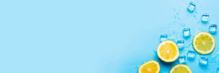 juicy fresh yellow cut lemon and ice cubes on a blue background. Top view, flat lay. Banner.