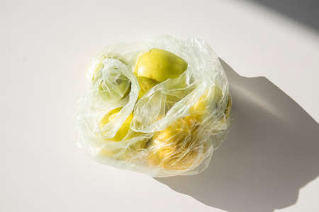 Fresh apples in a plastic bag on a white table. top view, flat layの写真素材