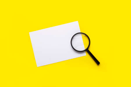 magnifying glass and blank white sheet on a yellow background.の写真素材
