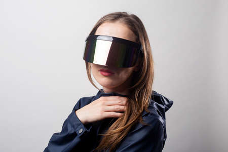 Style woman in virtual reality glasses and in a blue jacket on a light background.