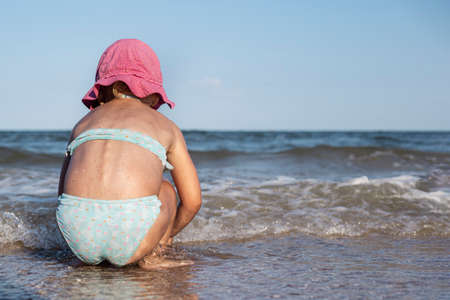 Little child girl in a swimsuit is played near the seaの写真素材
