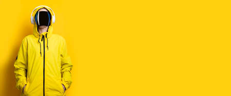 Young woman in cyberpunk glasses mask with headphones in a yellow jacket on a yellow background. Banner.の写真素材