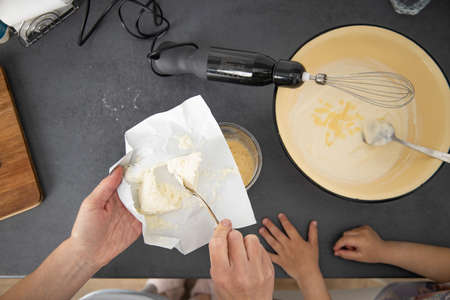 Woman with a mixer beats dough for baking, adding cottage cheese. Top view, flat lay.