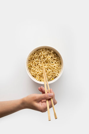 Chinese noodles in a paper mask with wooden chopsticks on a white background. Top view, fly lay.の写真素材