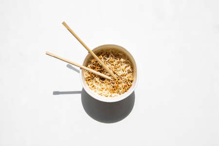 Chinese noodles in a cardboard bowl on a white background. Top view, fly lay.の写真素材