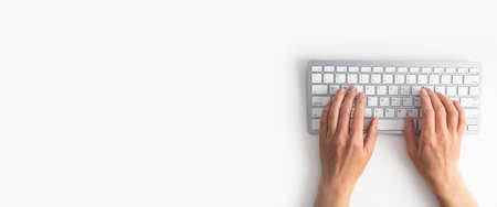 Female hands on the keyboard on a white background. Top view, flat lay. Banner.