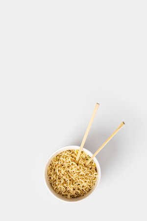 Chinese noodles in a paper mask with wooden chopsticks on a white background.Top view, flay lay.