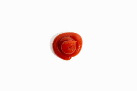 Ketchup red sauce is poured on a white background. Top view, flat lay.