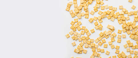 Crispy square shaped cracker scattered on white background. Top view, flat lay. Banner.
