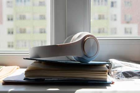 White wireless headphones lie on the diary on the windowsill.の写真素材