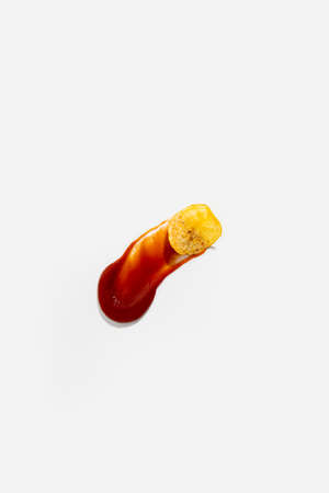 Potato chips in ketchup sauce on a white background. Top view, flat lay.の写真素材