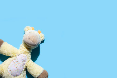 Children's soft toy giraffe on a blue background. Top view, flat lay.の写真素材