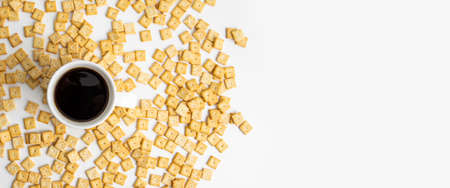 Coffee on the background of a scattered crispy cracker on a white table. Top view, flat lay. Banner.の写真素材