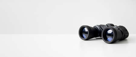 Black binoculars lying on a white background. side view. Banner.の写真素材