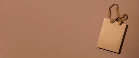 One package of gift craft brown on brown craft background. Banner. Top view, flat lay.