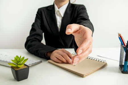 Business woman stretches out her hand while sitting at the desk in the office.の写真素材