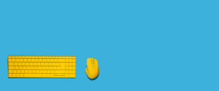 Yellow keyboard and yellow computer mouse on a blue background. Top view, flat lay. Banner.の写真素材