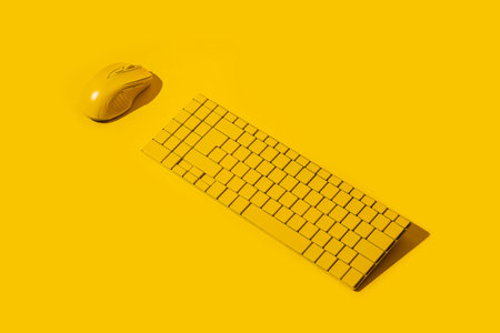 Yellow wireless keyboard and yellow computer mouse on a yellow background.の写真素材