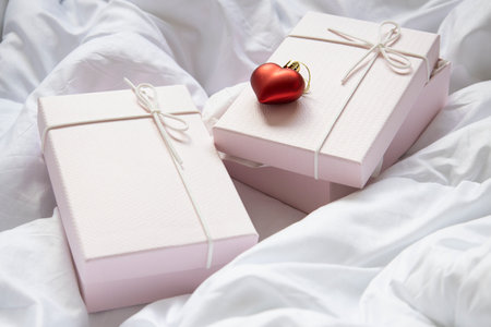 Gift boxes and decorative heart christmas toy on crumpled white fabric.
