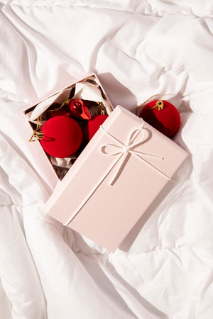 Gift box with christmas toys on white cloth. Top view, flat lay.