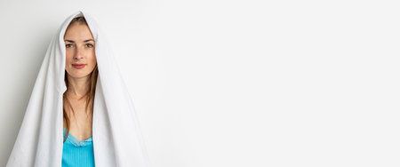 Smiling young woman covering her head with a sheet on a white background. Banner.