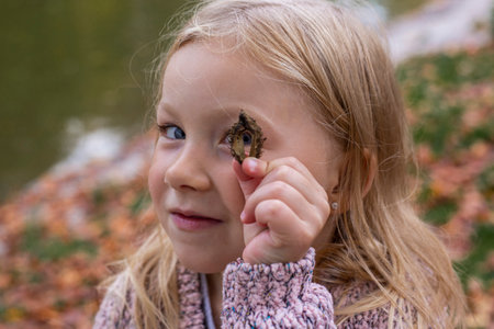 Smiling blonde baby girl playing in autumn park. top view.の写真素材