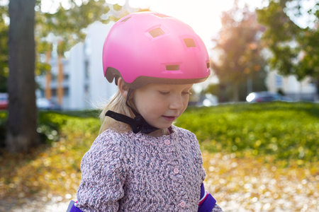Child girl in a pink helmet in protection in the park.の写真素材