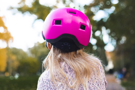 Child girl in a pink helmet from behind in the park.の写真素材