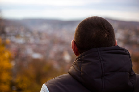 Young man sitting with his back looking at the panoramic view of the city.の写真素材