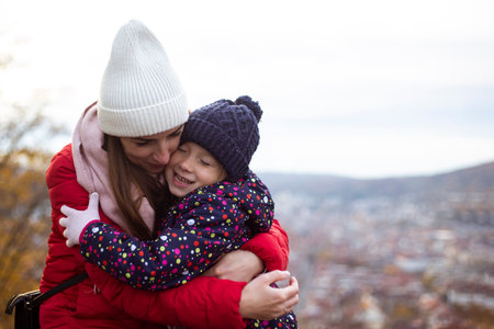 Joyful mother hugging her little daughter against the backdrop of a panoramic view.の写真素材
