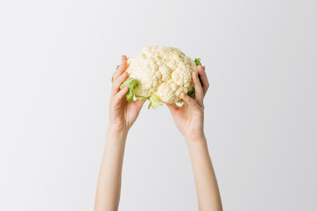 Female hands raised up cauliflower on a white background.の写真素材