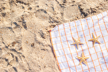 Golden starfish on a bedspread on a sandy beach. Top view, flat lay.の写真素材