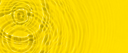 Drops fall on yellow water by sunlight. Top view, flat lay. Banner.の写真素材