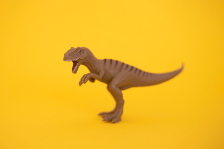 Plastic dinosaur toy on yellow background.の写真素材
