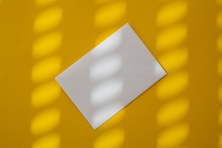 White envelope under sunlight on a yellow background. Top view, flat lay.の写真素材
