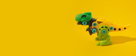 Plastic dinosaur toy on yellow background. Banner.の写真素材