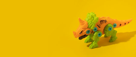 Plastic dinosaur toy on yellow background. Banner.の写真素材