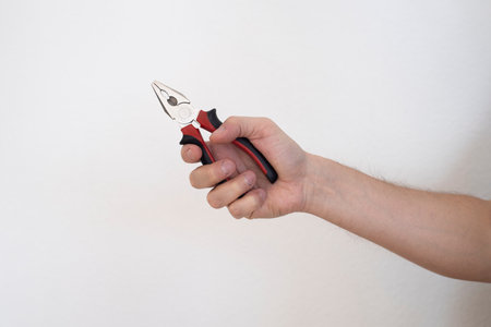 Man's hand holding pliers on a white background.の写真素材