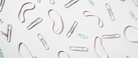 Paper clips and rubber bands stationery on a white background. Top view, flat lay. Banner.