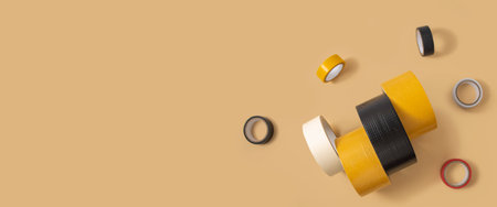 Construction colored adhesive tape, electrical insulating tape on a light background. Top view, flat lay. Banner.の写真素材