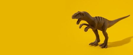 Plastic dinosaur toy on yellow background. Banner.の写真素材