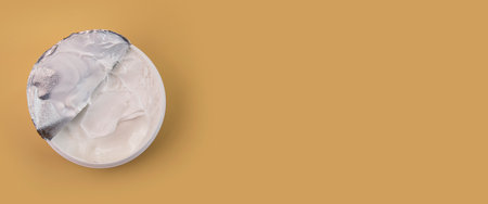 Opened cream as a sample of a cosmetic product on a beige background. Top view, flat lay. Banner.の写真素材