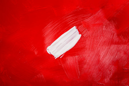 A smear of white paint on a red background. Top view, flat lay.の写真素材