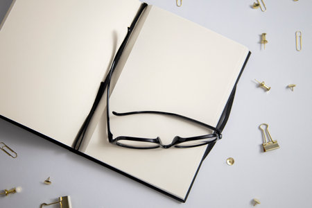 Open diary, glasses, gold paper clips, paper clips on a white background. Top view, flat lay.の写真素材
