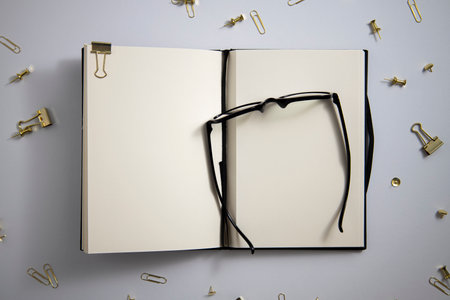 Open diary, glasses, gold paper clips, paper clips on a white background. Top view, flat lay.の写真素材