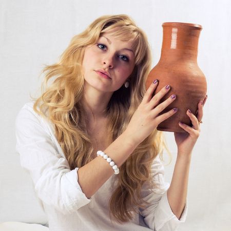 Portrait of a young blonde girl with jug in the white backgroundの写真素材